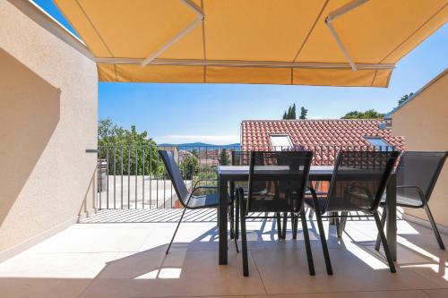 een patio met een tafel en stoelen op een balkon bij Apartments Mila in Sveti Filip i Jakov