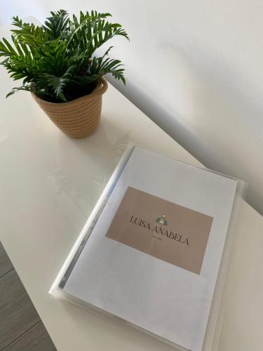 a book on a table next to a plant at Vila Luisa Anabela Piscine et Jacuzzi only family in Albufeira