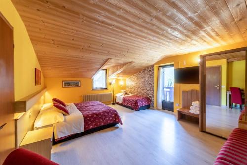 1 dormitorio con 2 camas y techo de madera en Hotel Alpino Wellness & Spa, en Peio Fonti