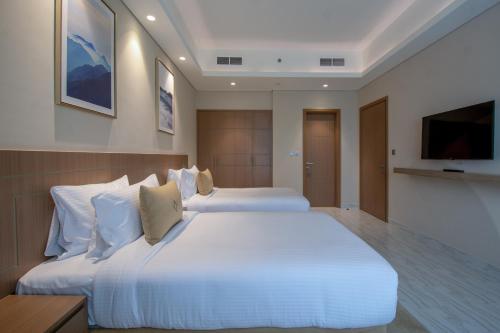 a hotel room with two beds and a television at Jood Hotel Apartments in Dubai