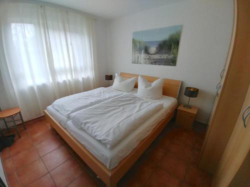 uma cama com lençóis brancos e almofadas num quarto em Fewo65 Residenz am Strand em Zingst