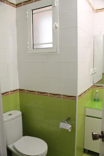een groene en witte badkamer met een toilet en een raam bij Apartamento Carlota beach carihuela in Torremolinos