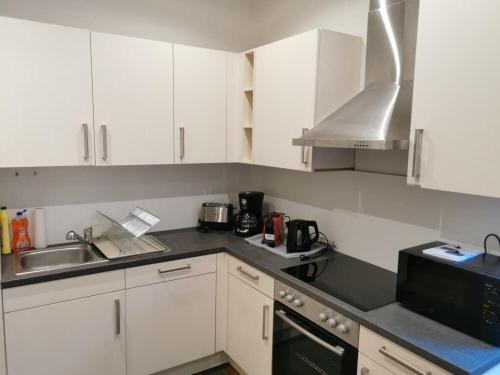 a kitchen with white cabinets and a sink and a microwave at Wohnung mit Parkplatz und Garten in Donawitz