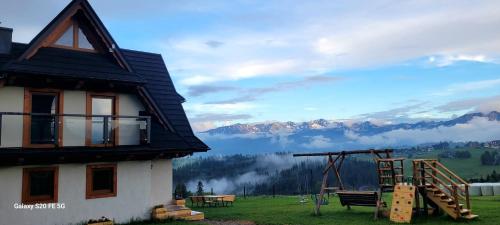 a house with a playground in front of a mountain at NOWA CHATA in Bustryk