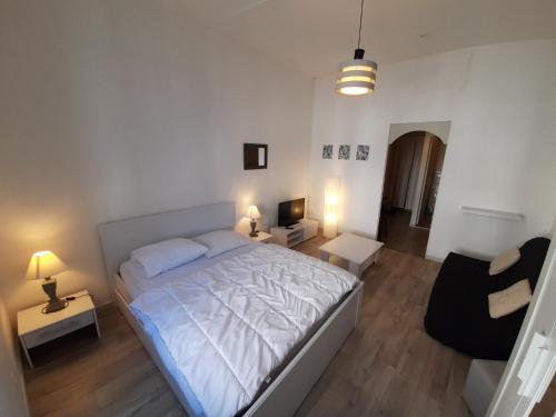 a bedroom with a white bed and a living room at Meublé de tourisme Sejour-La-Roche Pasteur in La Roche-Posay