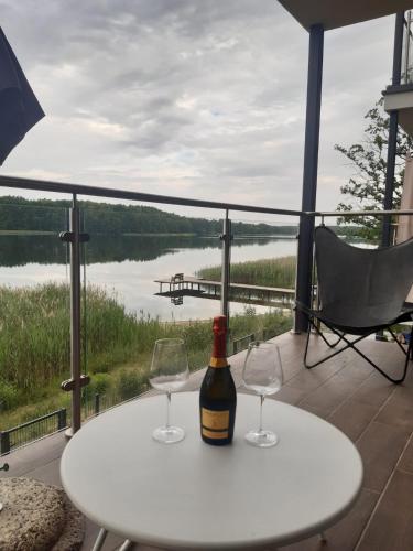 a bottle of wine on a table with two wine glasses at Apartament nr 9 Mazurskie Klimaty in Tomaszkowo