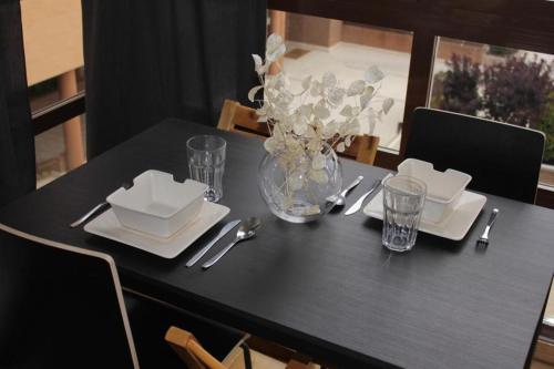 einen schwarzen Tisch mit Tellern und Gläsern und eine Vase Blumen in der Unterkunft APARTAMENTO BARAJAS-IFEMA in Madrid