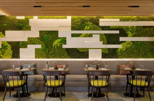 ein Restaurant mit vier Tischen und einer grünen Wand in der Unterkunft Sheraton Amsterdam Airport Hotel and Conference Center in Schiphol