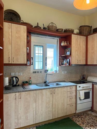 een keuken met houten kasten, een wastafel en een raam bij Traditional home in Mauromati in Mavrommátion