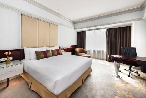 a hotel room with a large bed and a desk at Wyndham Casablanca Jakarta in Jakarta