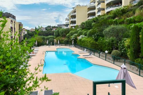 une grande piscine bleue avec des chaises et des arbres dans l'établissement Happyfew Le Flora, à Nice