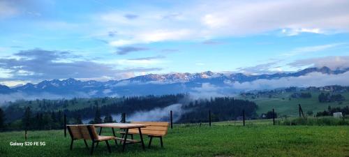 a table and two chairs in a field with mountains at NOWA CHATA in Bustryk