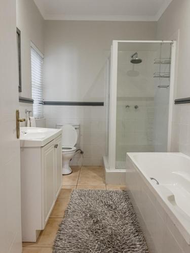 a bathroom with a tub and a sink and a toilet at 4278 River Club in Plettenberg Bay