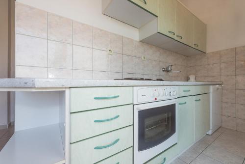 a kitchen with white cabinets and a stove top oven at Apartments Remini in Grebaštica