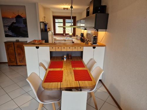 cocina con mesa de madera y sillas blancas en Au calme du Jura, en Saint-Cergue