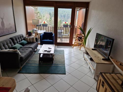 ein Wohnzimmer mit einem Sofa und einem Tisch in der Unterkunft Au calme du Jura in Saint-Cergue