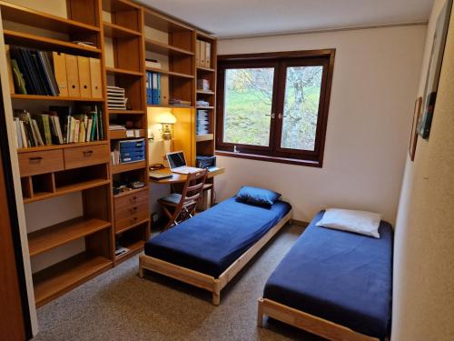 1 dormitorio con 2 camas y escritorio con ordenador en Au calme du Jura, en Saint-Cergue