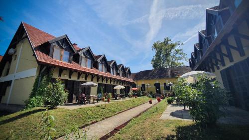 a group of buildings with tables and umbrellas at Harmónia Apartmanház in Balatonlelle