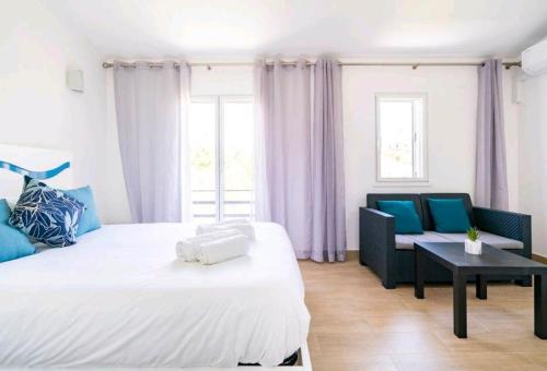 - une chambre avec un grand lit blanc et un canapé dans l'établissement Marina Holiday House, à Quarteira
