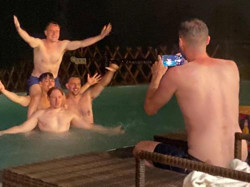 a man taking a picture of a group of men in a swimming pool at Zhangjiajie National Park Nvue Resorts in Zhangjiajie