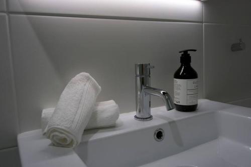 um lavatório de casa de banho com uma garrafa de sabão e toalhas em Stylish Lux Modern 2B2B Apt at Dickson heart em Camberra
