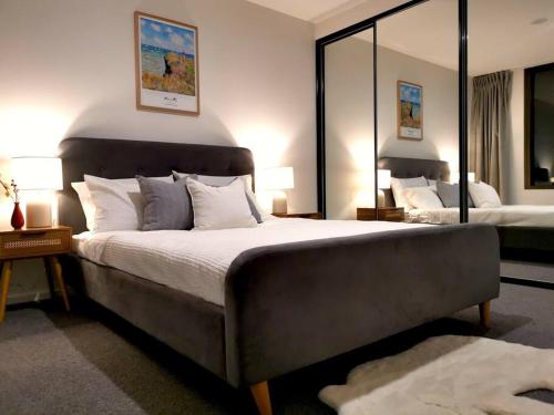 um quarto com uma cama grande e um espelho grande em Stylish Lux Modern 2B2B Apt at Dickson heart em Camberra