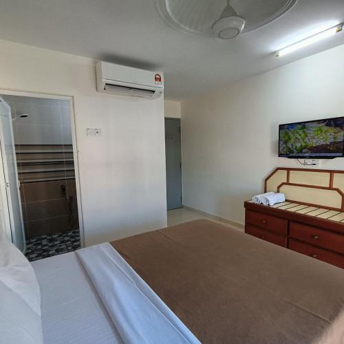 a bedroom with a bed and a tv on the wall at Kota Lodge Guest House in Melaka