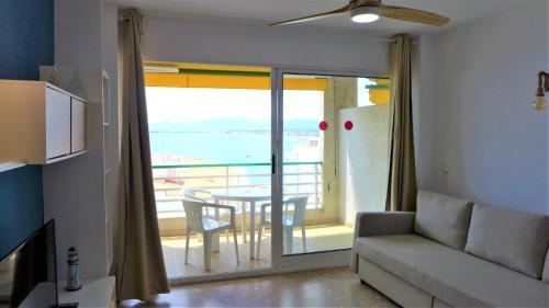 a living room with a couch and a balcony with a table at Apartamentos Paradís Palmyra in Salou