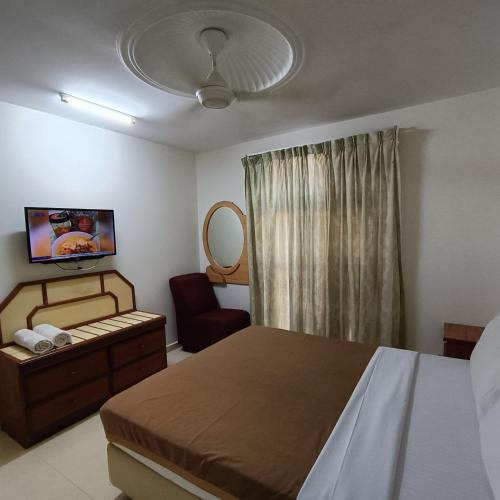 a bedroom with a bed and a chair and a mirror at Kota Lodge Guest House in Melaka