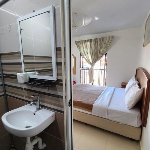 a bathroom with a bed and a sink and a mirror at Kota Lodge Guest House in Melaka