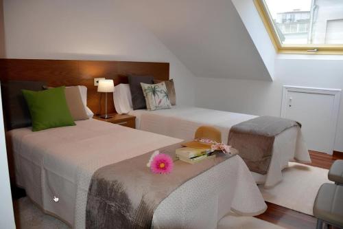Un dormitorio con 2 camas y una mesa con una flor. en HHC - Duplex Concheiros, 4 bedrooms, 3 bathroom, a 700m de la Catedral, en Santiago de Compostela