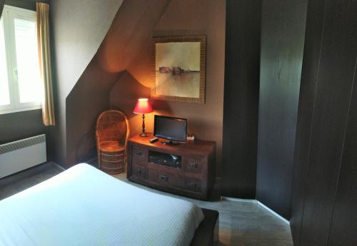 a bedroom with a bed and a desk with a computer on it at L'échappée belle in Touques