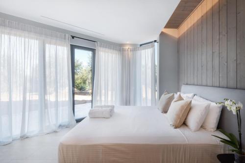 a bedroom with a large white bed with white pillows at Villa Artemis in Ágios Stéfanos