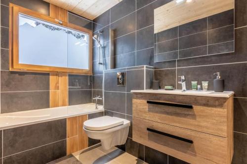 ein Bad mit einem WC, einem Waschbecken und einem Fenster in der Unterkunft Apartment Les Cerfs in Megève