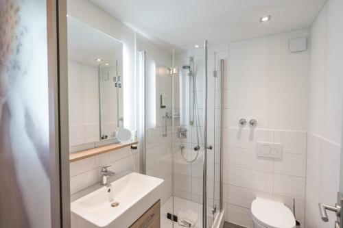 a bathroom with a shower and a sink and a toilet at Wohlfühlhotel Frohsinn in Fischen