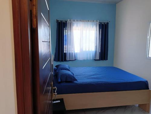 een slaapkamer met een bed met blauwe lakens en een raam bij Villa de vacances privative in Toamasina