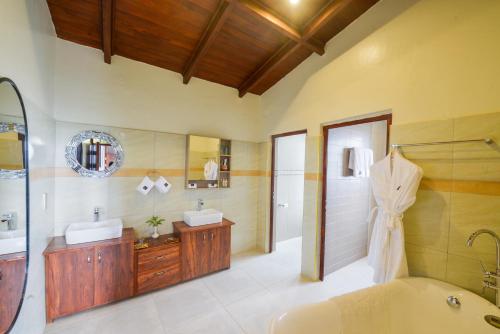 Kisoro的住宿－Gorilla Heights Lodge，带浴缸、两个盥洗盆和淋浴的浴室。