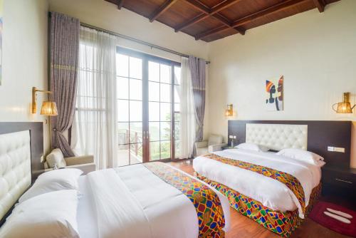 a bedroom with two beds and a large window at Gorilla Heights Lodge in Kisoro