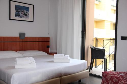 sypialnia z 2 łóżkami i krzesłem oraz balkonem w obiekcie Hotel Nettunia w Rimini