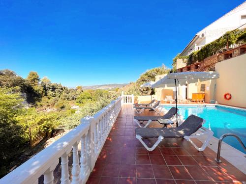 a balcony with a pool and chairs and an umbrella at Villa Ignacia B&B - Habitaciones & Apartamentos en Plena Naturaleza in Arriate