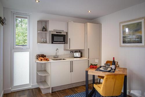 a kitchen with white cabinets and a table and a counter at Lake District Woodland Pods - Winster, Bowness-on-Windermere in Winster