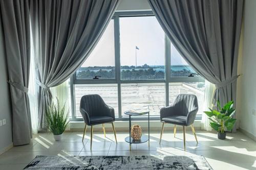 two chairs and a table in front of a large window at Super 2 Bedroom Sea View in Abu Dhabi