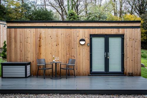 a wooden building with a table and chairs on a deck at Lake District Woodland Pods - Winster, Bowness-on-Windermere in Winster