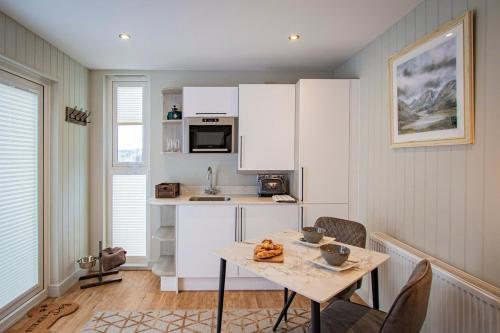 a kitchen with white cabinets and a table with chairs at Lake District Woodland Pods - Winster, Bowness-on-Windermere in Winster