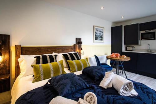 a bedroom with a bed with pillows and a kitchen at Lake District Woodland Pods - Winster, Bowness-on-Windermere in Winster