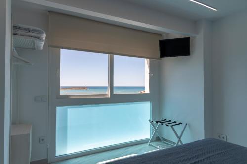 a bedroom with a window with a view of the ocean at Hostal Boutique La Mar Serena in Peniscola