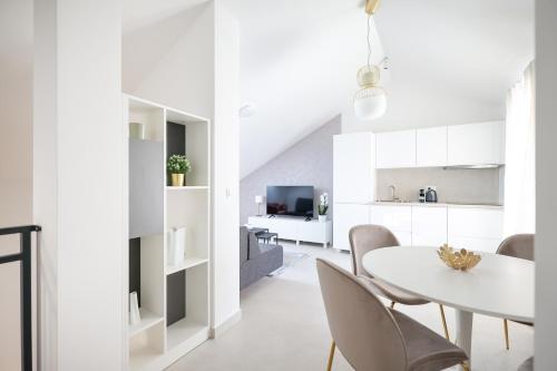 a white kitchen and dining room with a white table and chairs at Apartments Mila in Sveti Filip i Jakov