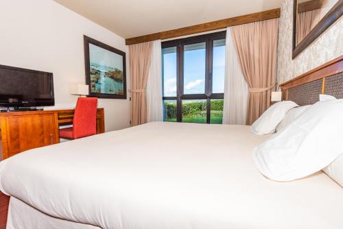 ein Schlafzimmer mit einem großen weißen Bett und einem Fenster in der Unterkunft Hosteria de Torazo Nature Hotel & Spa in Torazo