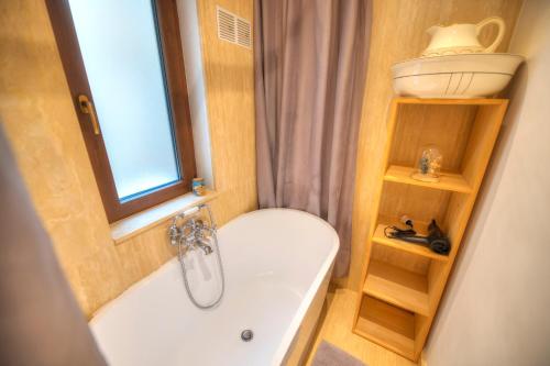 ein Bad mit einer Badewanne, einem WC und einem Fenster in der Unterkunft Comfy 1 bedroom - Sun terrace & sea views GBUH1-1 in Valletta