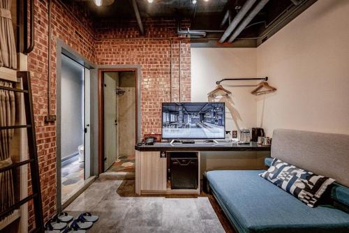 Hotel Leisure Chiayi في مدينة تشيايي: غرفة مع أريكة ومكتب مع تلفزيون